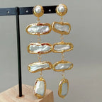 Gold and pearl earrings on a gray background