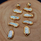 Gold and stone earrings on a wooden surface