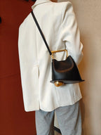 Person wearing a white coat with a black handbag featuring gold accents.