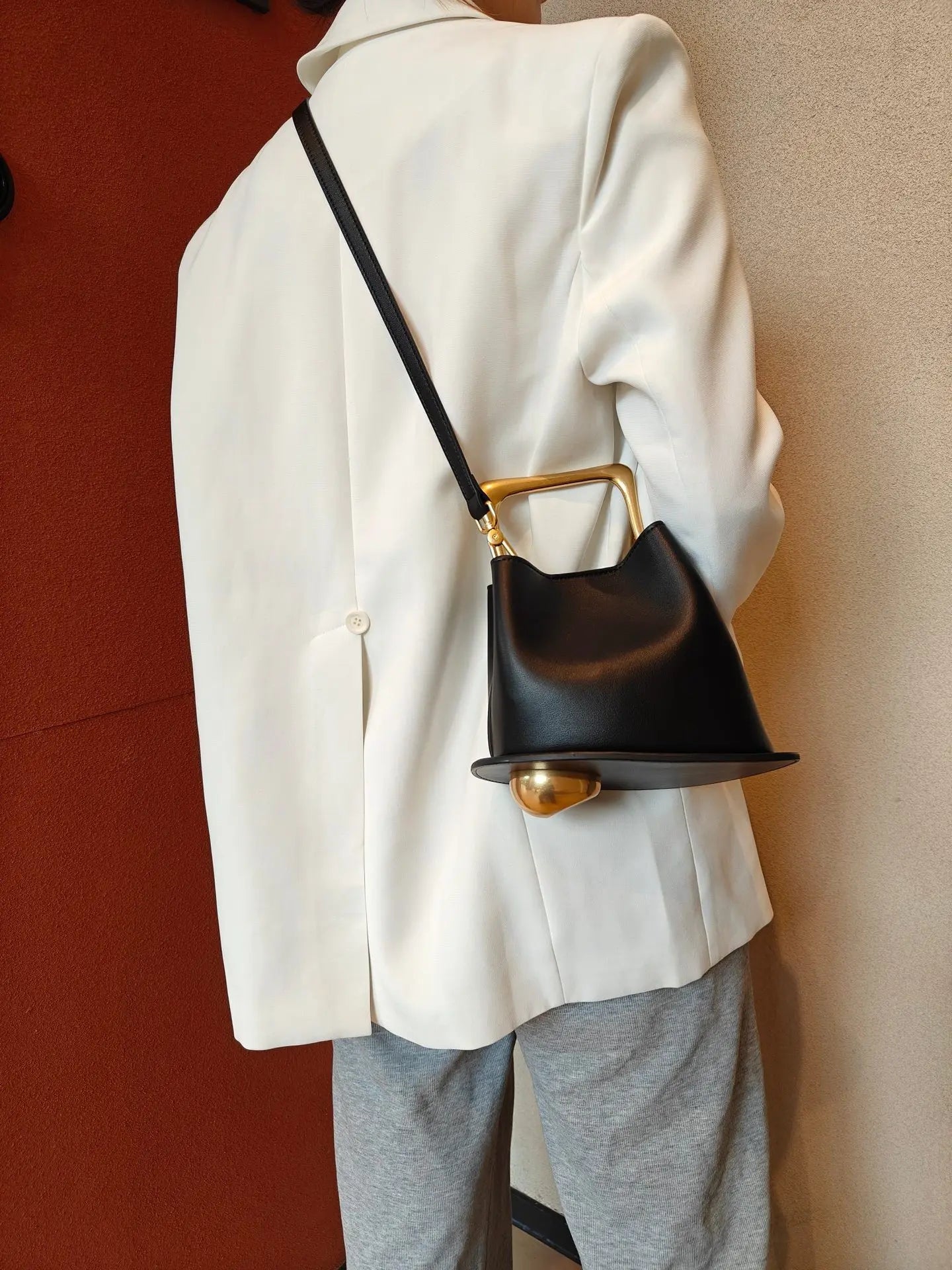 Person wearing a white coat with a black handbag featuring gold accents.
