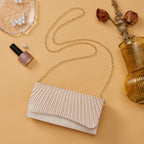 Beige pleated handbag with gold chain on a beige background with nail polish and decorative elements.