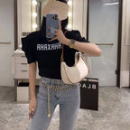 Person wearing a black t-shirt with 'AHAXAHA' text, light blue jeans, and a beige handbag in a mirror selfie.