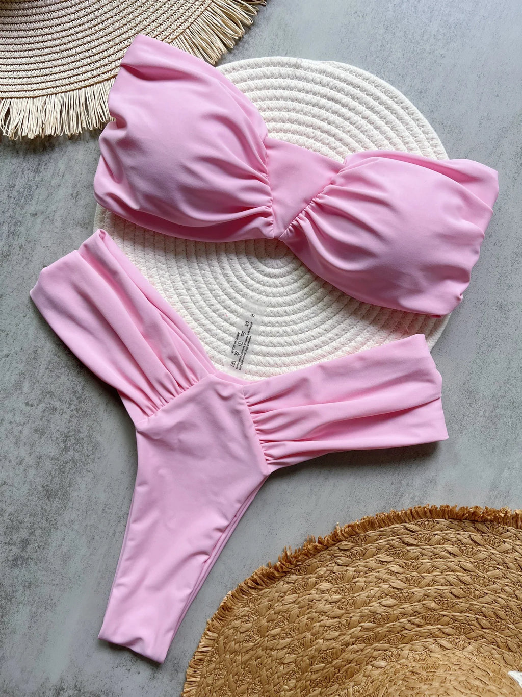Pink bikini set on a textured surface with woven mat