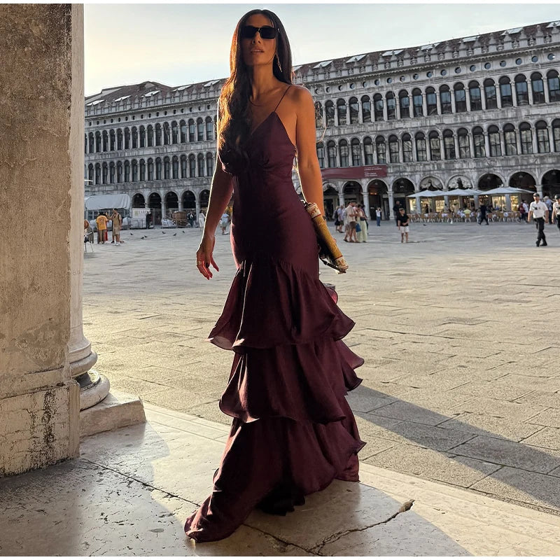 Woman in a purple dress standing in a historic square with architectural buildings in the background.