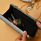 Silver clutch with makeup items on a beige background