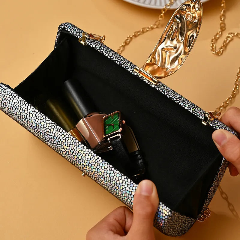 Silver clutch with makeup items on a beige background