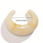 Beige crescent-shaped earring with measurement label on a white background