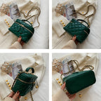 Green quilted handbag held by a person on a white surface with newspapers and pearls.
