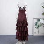 Maroon dress on a mannequin against a white wall with a plant in the corner