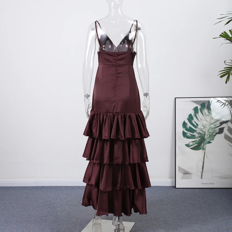 Maroon dress on a mannequin against a white wall with a plant in the corner