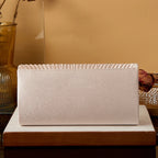 Beige clutch bag on a wooden surface with a blurred background