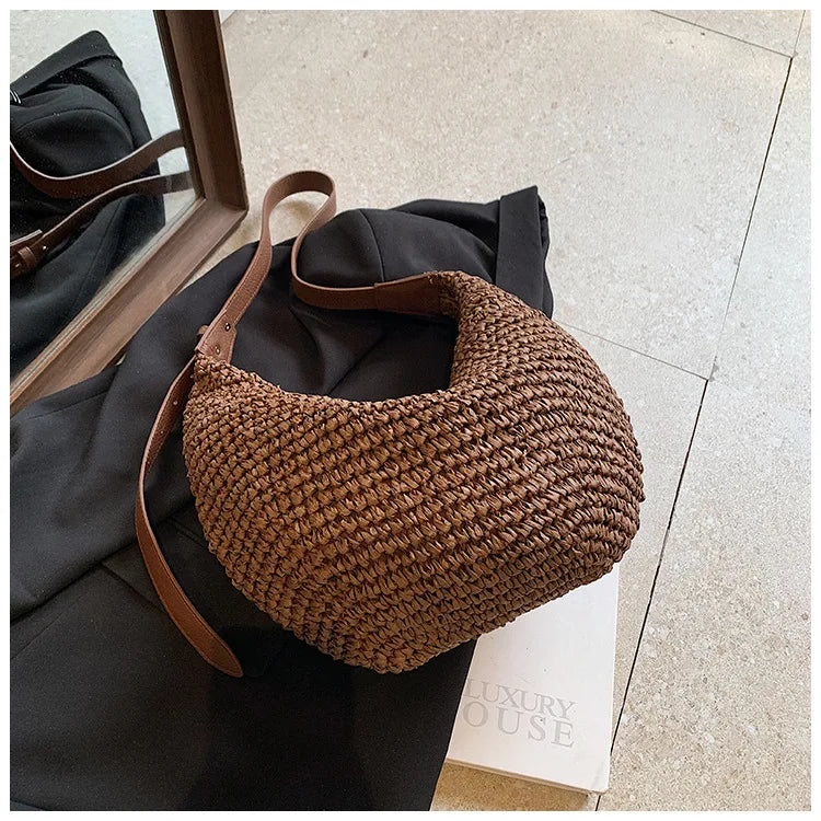 Brown woven handbag with leather strap on a black garment 