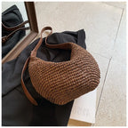 Brown woven handbag with leather strap on a black garment 