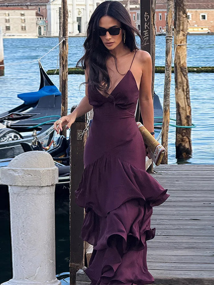 Woman in a purple dress standing by a waterfront with gondolas in the background