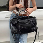 Person holding a black handbag with a blurred background