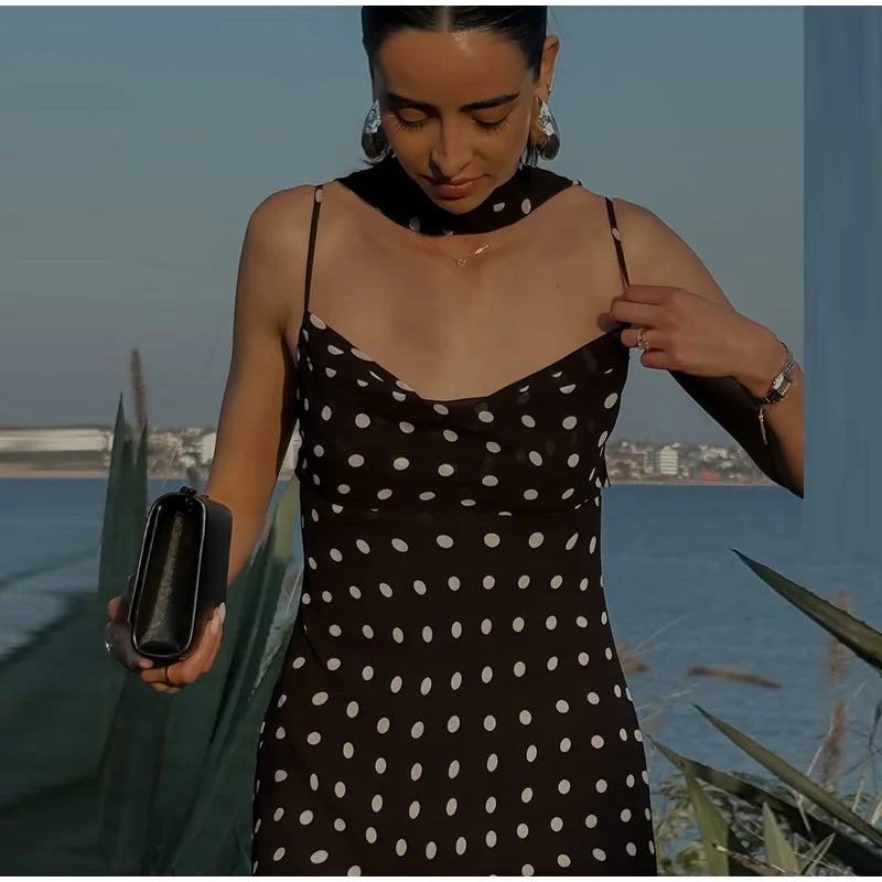 Woman in a polka dot dress holding a clutch by the water