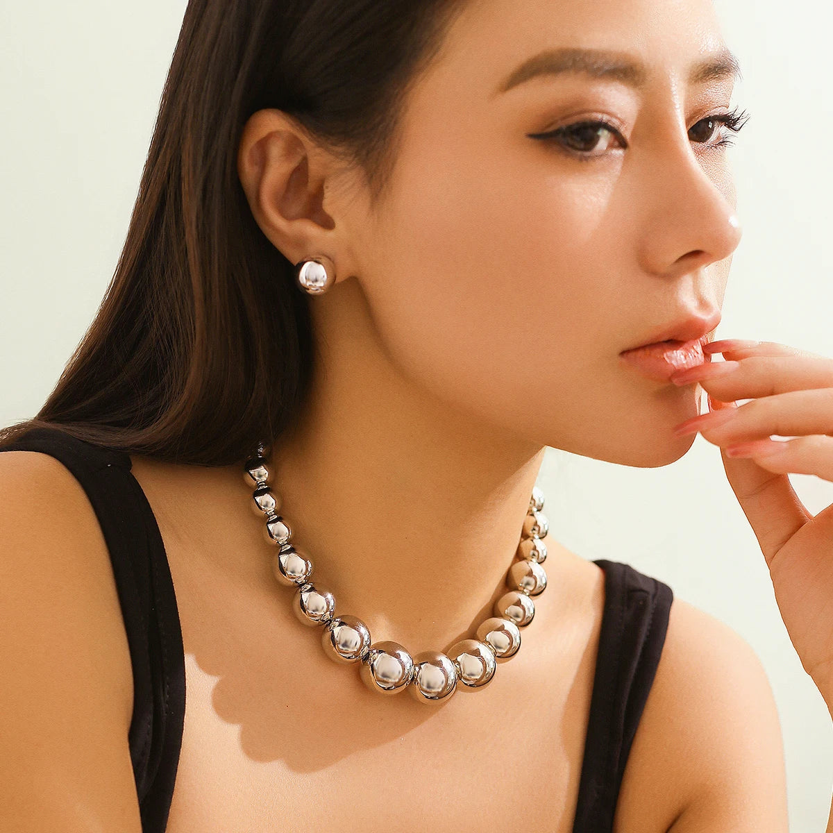 Woman wearing a silver necklace and earrings against a neutral background