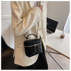 Person holding a black quilted handbag in an office setting
