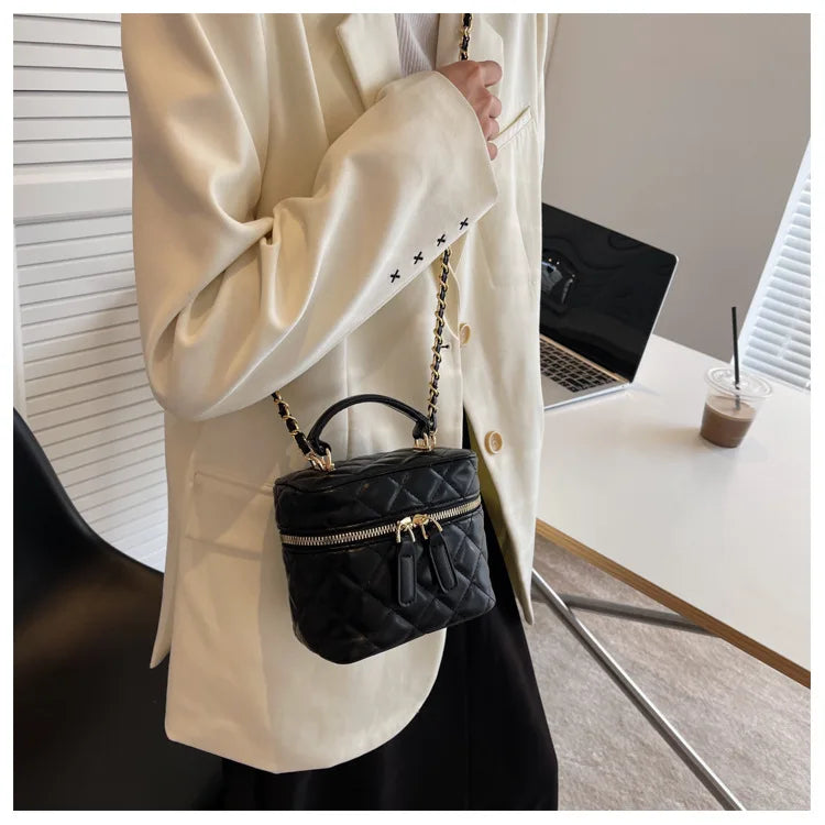 Person holding a black quilted handbag in an office setting