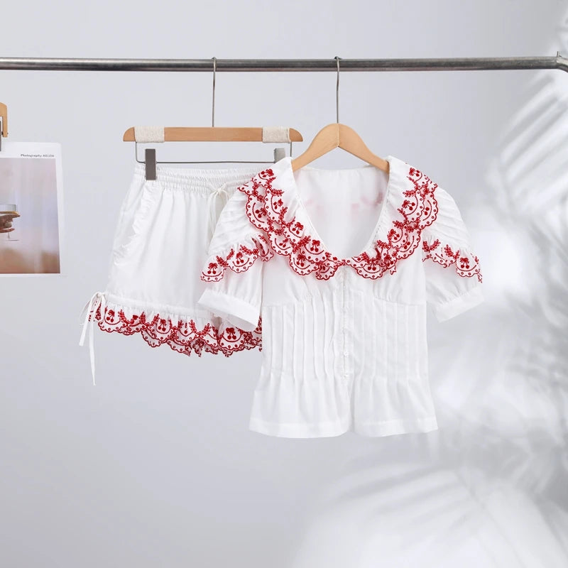 White blouse with red lace details on a hanger against a white background