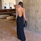 Woman in a black dress with open back standing in a room with patterned floor and wooden wall.