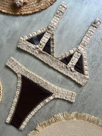 Beige and black bikini set on a textured surface with straw hats.