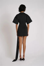 Black dress with a long train worn by a model on a white background