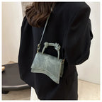 Person wearing a black outfit with a light blue handbag over their shoulder.