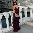 Woman in a deep purple dress standing on a stone bridge over water.