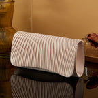 Beige clutch bag on a reflective surface with a warm-toned background