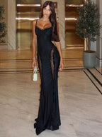 Woman in a black evening gown standing in an elegant interior setting.