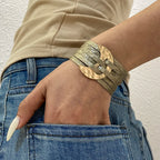 Person wearing a gold bracelet on a neutral background