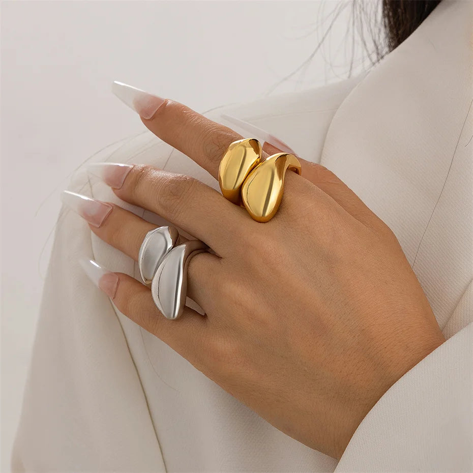 Hand wearing gold and silver rings on a light background