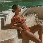 Woman in a polka dot swimsuit sitting by a pool