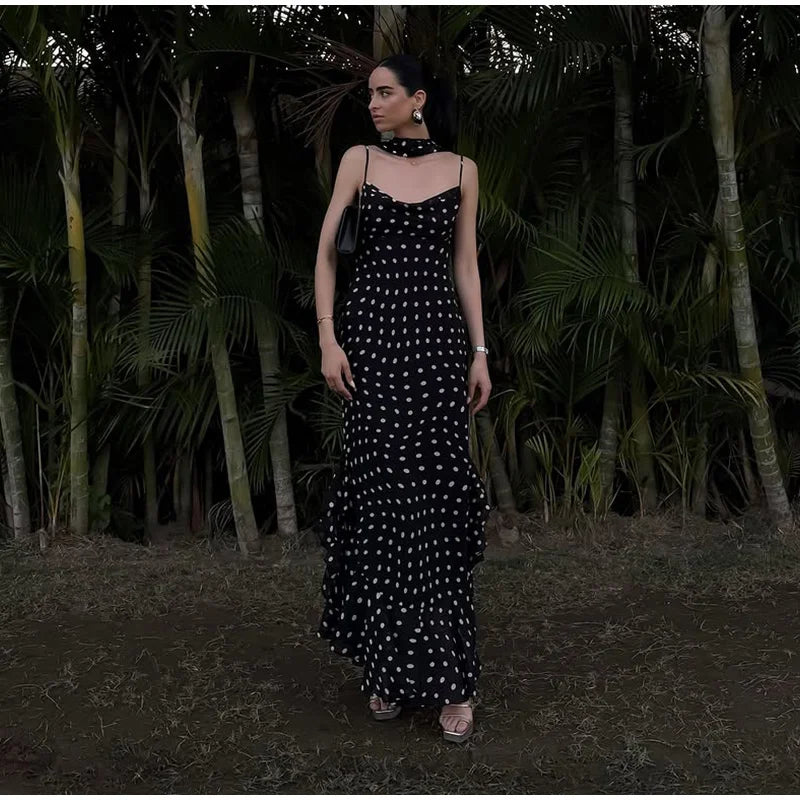 Woman in a black and white polka dot dress standing in a forest setting