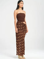 Woman wearing a brown strapless top and polka dot skirt on a white background