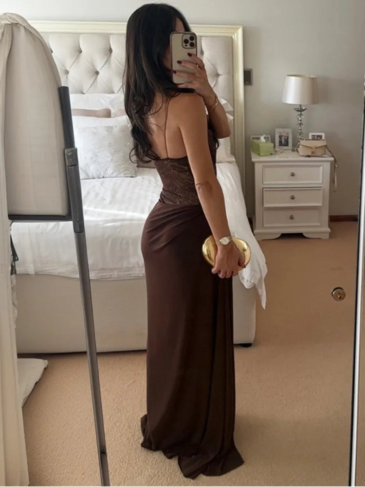 Woman in a brown dress taking a mirror selfie in a bedroom.