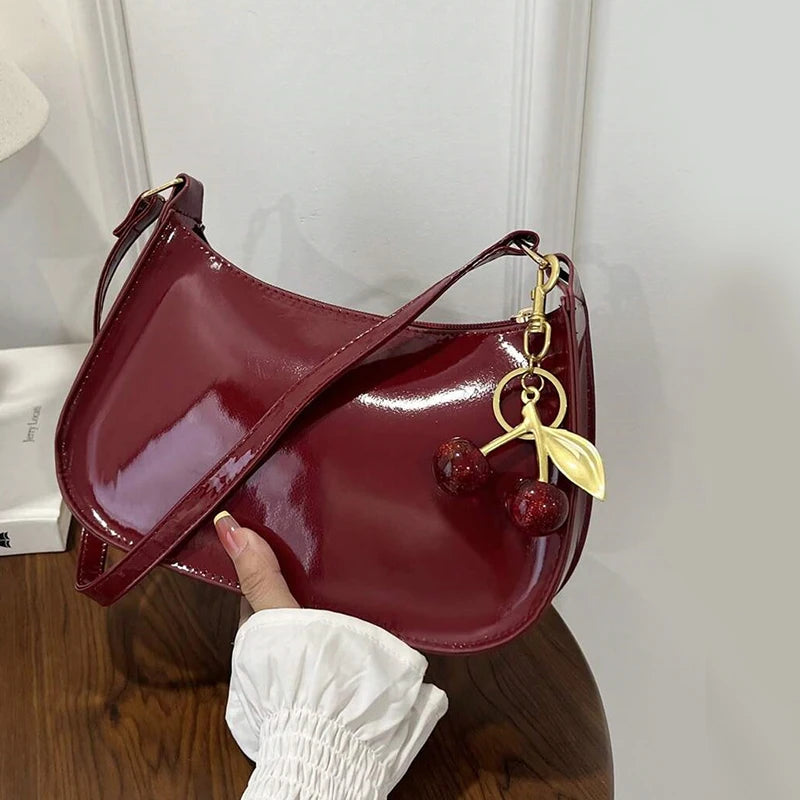 Red handbag with a cherry charm on a wooden surface