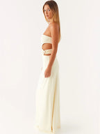 Woman wearing a white strapless top and long skirt on a white background