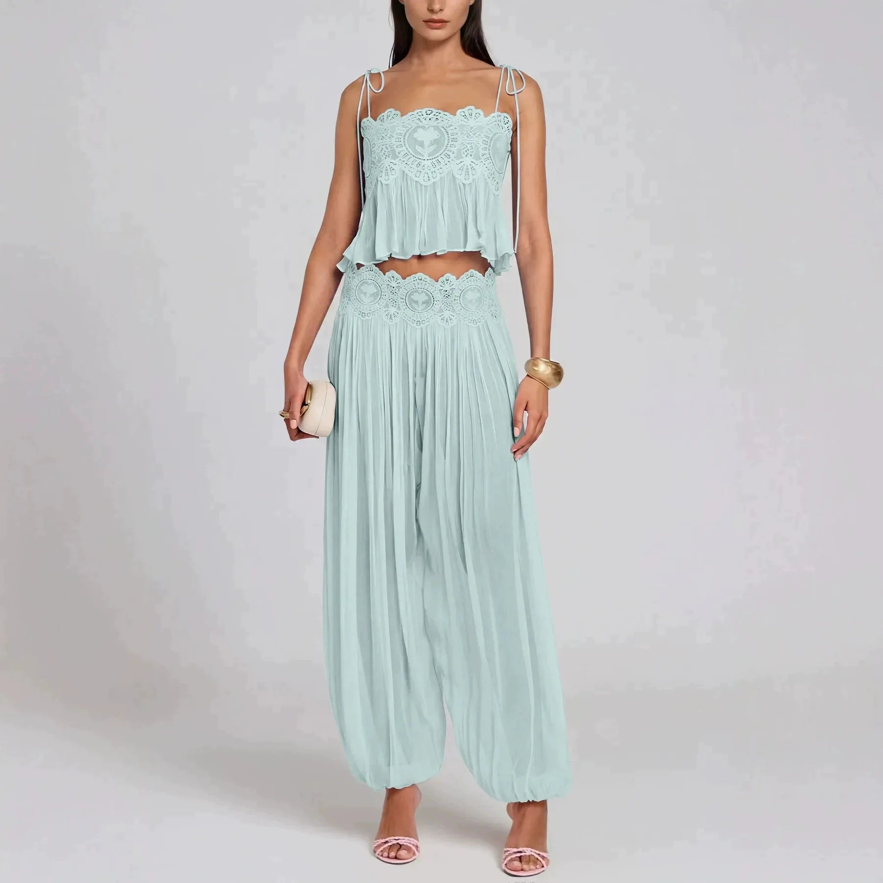 A woman models a light mint green two-piece set consisting of a lace-trimmed crop top with ruffles and matching pleated harem pants, against a plain light gray studio background.
