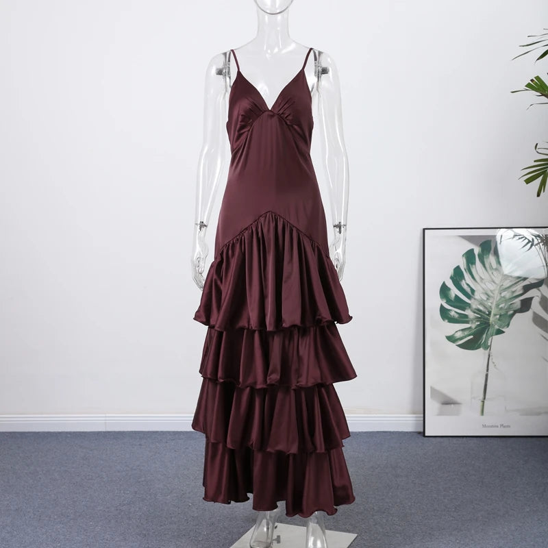 Burgundy tiered dress on a mannequin against a white wall with a plant in the corner.