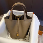 Grey handbag with gold lock on a white surface