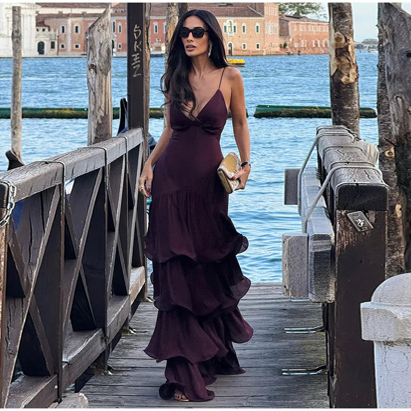 Woman in a dark purple dress standing on a wooden dock by water