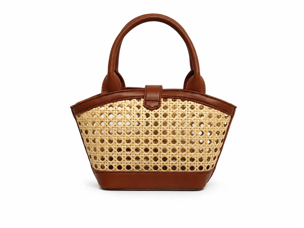 A structured handbag with a natural woven cane body and brown leather trim, featuring dual top handles and a front strap closure, shown against a plain white background.