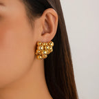 Gold bead earring worn by a person with a neutral background