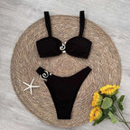 Black bikini set on a woven mat with sunflowers and a starfish