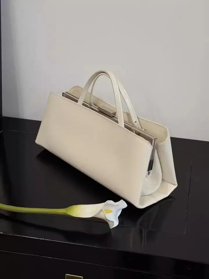 Beige handbag on a black surface with a white flower