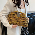 Person holding a brown woven handbag indoors