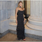 Woman in a black and white polka dot dress standing in a marble interior setting.