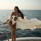 Woman in a white swimsuit with black accents on a boat with ocean view